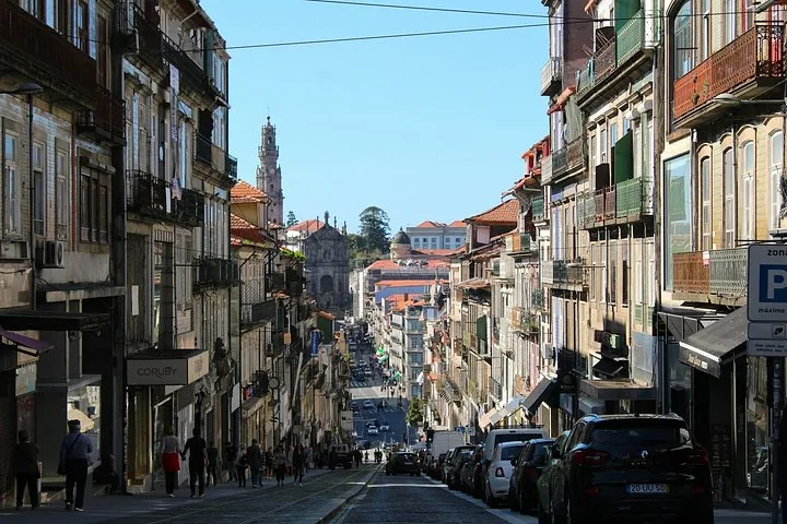 Una vista hacia abajo de una bulliciosa y estrecha calle de la ciudad flanqueada por edificios históricos.