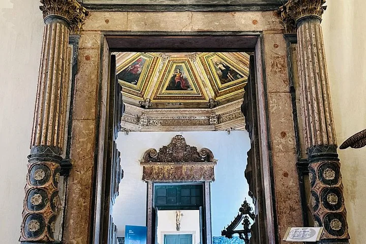 An ornate doorway looking into a room with painted ceilings and religious art.