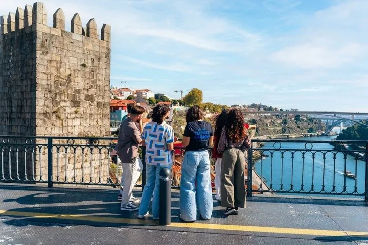 Un grupo contempla el río y el paisaje urbano desde la pasarela de un puente.